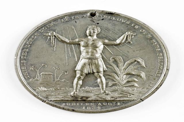 A large silver medallion with an image of a slave on it.