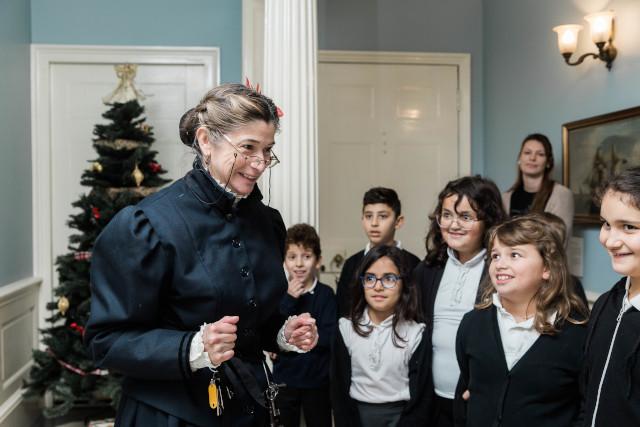 A woman in Victorian clothing talking to school children