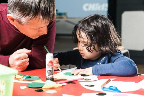 A man helping a child with crafts