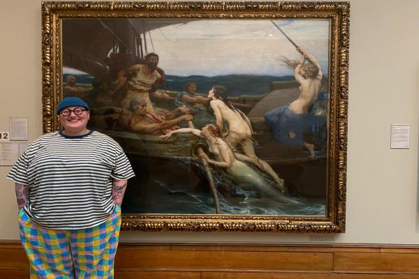 A person stood next to a large painting of Ulysses and the sirens.