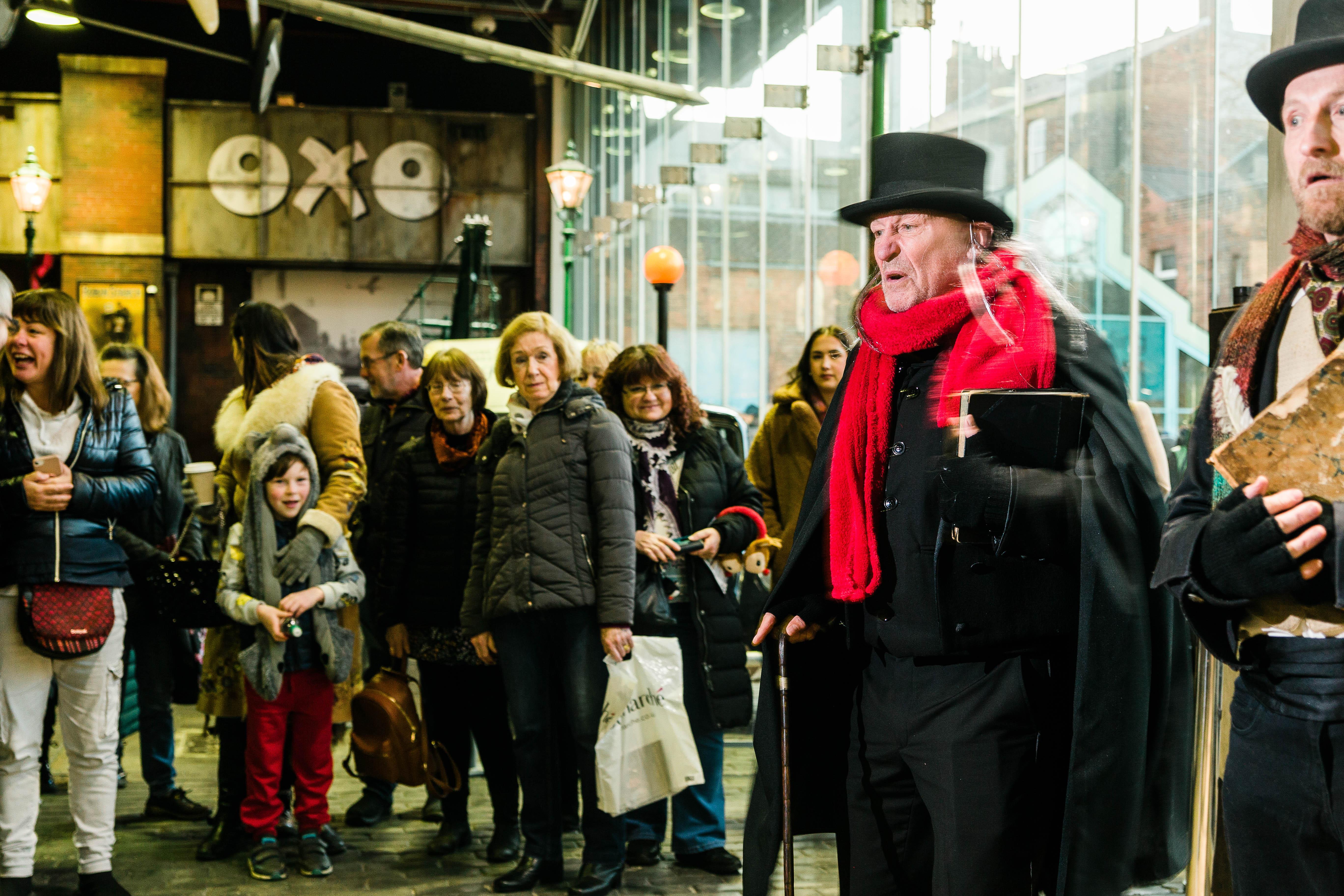 2 people dressed in Victorian Costume entertaining a crowd of people