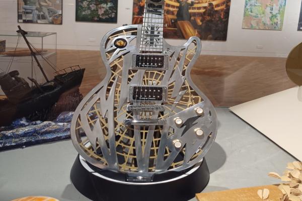 A metal guitar that has intricate etchings and cut-outs carved throughout